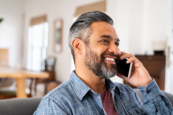 Man smiling while talking on phone at home