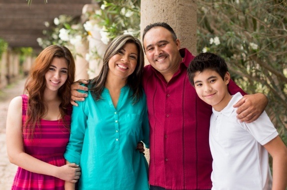 Family of four smiling under stone walkway with roof