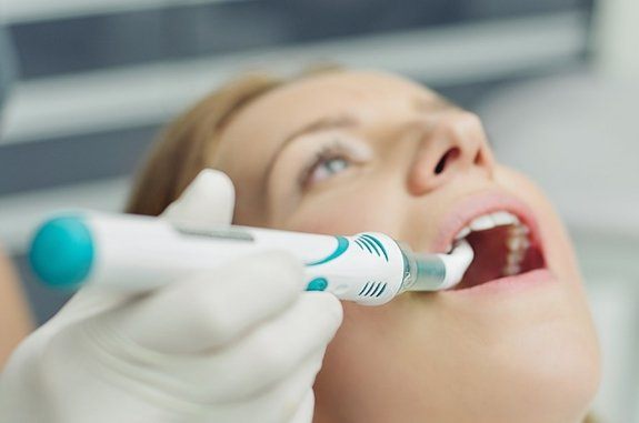 Dentist scanning a patient's mouth with advanced cavity detection system