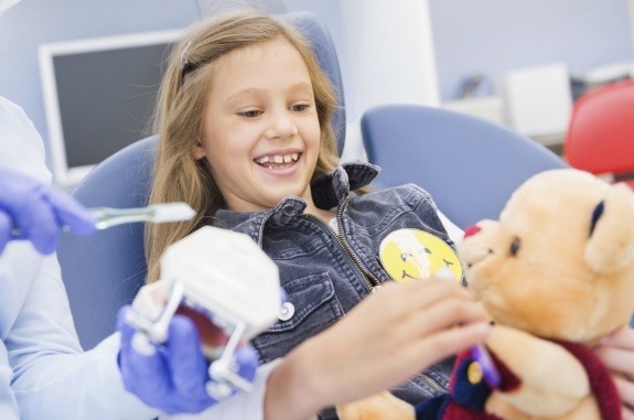 Girl holding teddy bear in dental chair