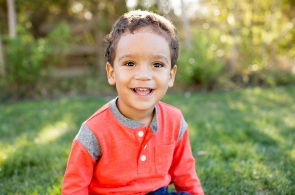 Young boy grinning outdoors on sunny day