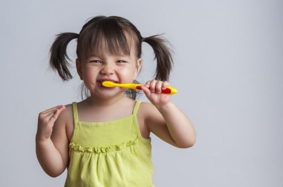 Young girl with pigtails brushing her teeth