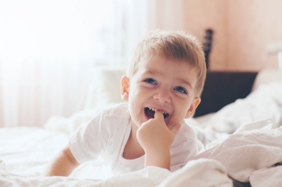 Young boy grinning while laying on bed