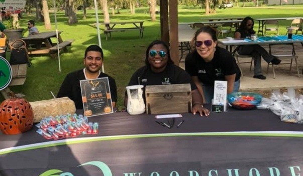 Three Clute dental team members sitting at table outdoors