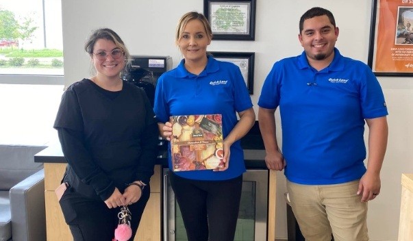 Three dental team members with charcuterie package in dental office