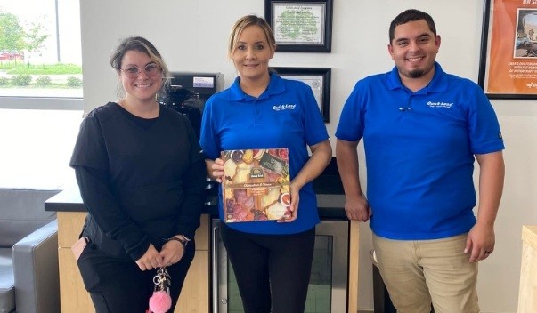 Three dental team members with charcuterie package in dental office