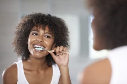 Woman brushing her teeth in front of bathroom mirror