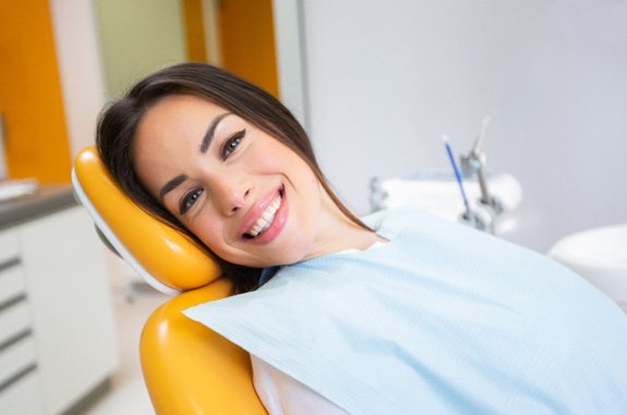 Female dental patient leaning back in chair and smiling 