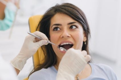 Woman having her mouth examined by dentist