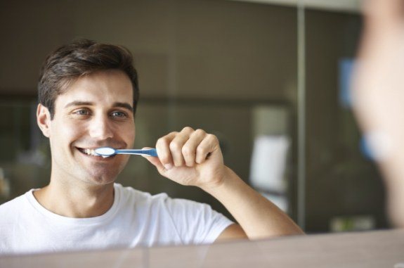 Man with dental crown in Clute brushing his teeth
