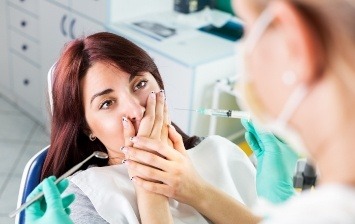 Woman covering her mouth in dental chair