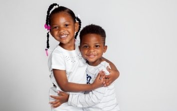 Young brother and sister hugging each other against white background