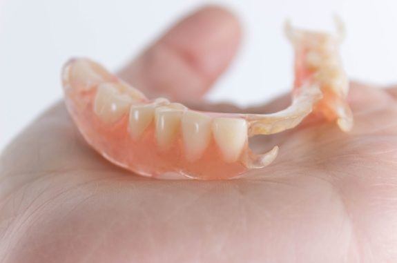 Person holding a partial denture in their hand