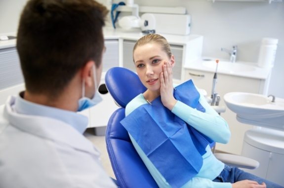 Woman holding her jaw in pain while visiting emergency dentist in Clute