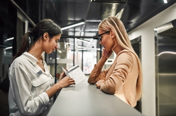 Woman showing a pamphlet to another woman from across desk