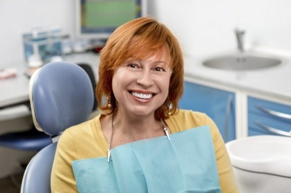Older redheaded woman smiling in dental chair