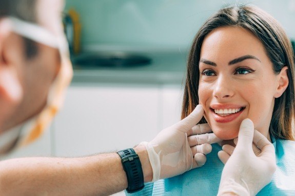 Dentist touching a patient's cheeks as she smiles