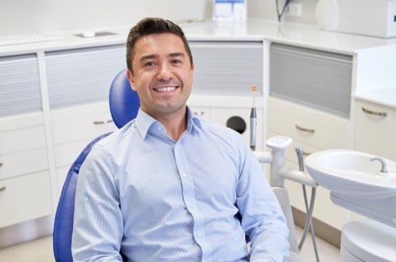 Man in light blue shirt smiling in dental chair