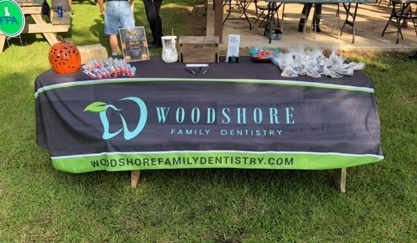 Table outdoors with cover that says Woodshore Family Dentistry