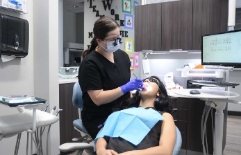 Dental team member shining light into patient's mouth