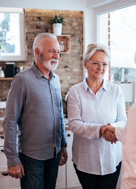 Person talking to senior man and woman while shaking hands with the woman