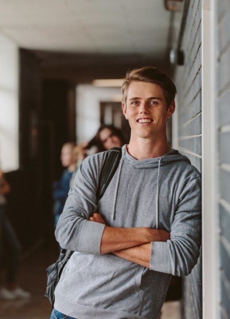 Teenage boy leaning against wall of high school hallway