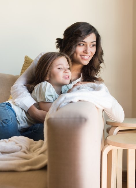 Mother cuddling with her toddler daughter on couch