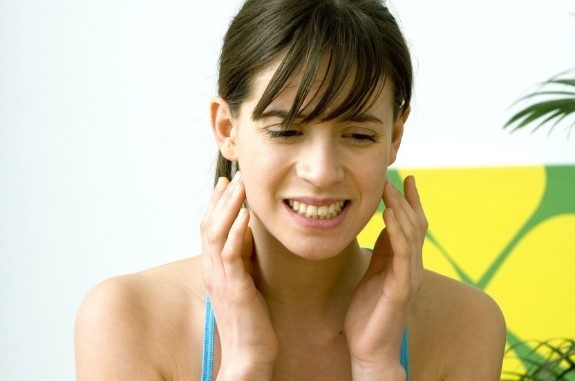 Woman holding both sides of her jaw in pain