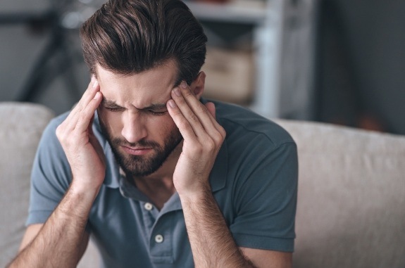 Man holding his temples with stressed expression on his face