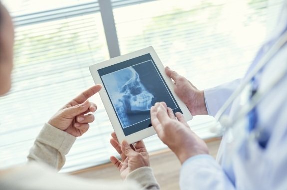 Dentist showing a patient a tablet with x rays of their jaw on it
