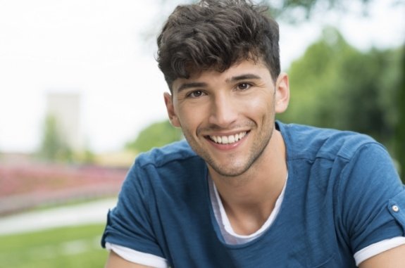 Young man in blue shirt smiling outdoors