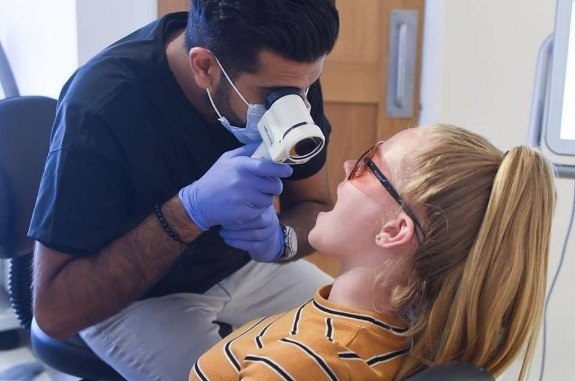 Dentist using velscope to perform an oral cancer screening