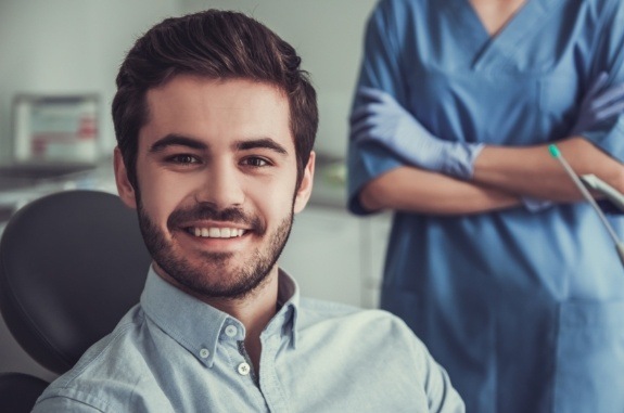 Young man with short beard smiling in dental chair