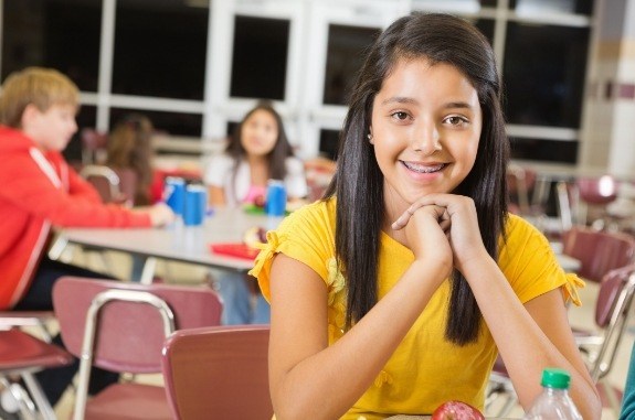 Smiling girl sitting at lunch table in school cafeteria