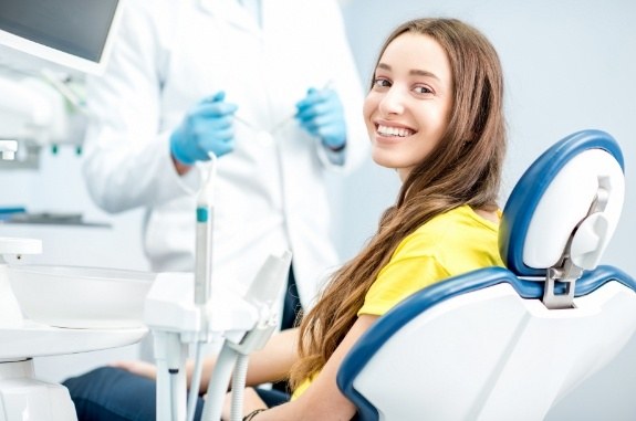 Smiling woman in dental chair wearing yellow blouse