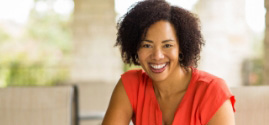 Woman in orange blouse smiling on couch