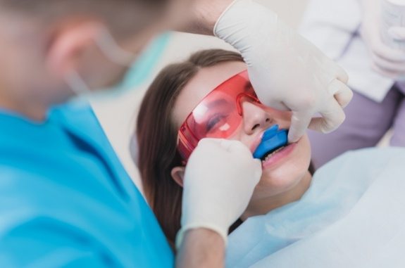 Young girl receiving fluoride treatment in dental office