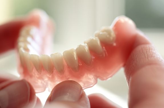 Person holding a full lower denture in their hands