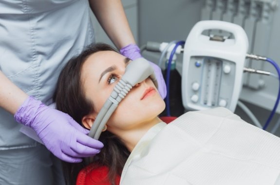 Woman in dental chair wearing nasal mask for nitrous oxide sedation dentistry in Clute