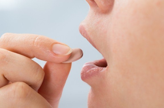 Close up of a person about to swallow a pill