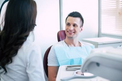 Man in dental chair talking to dental team member