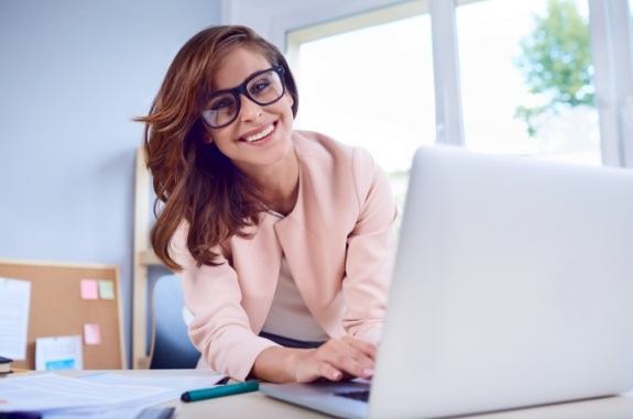 Smiling woman sitting at desk with laptop