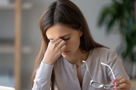 Woman pinching bridge of her nose in frustration