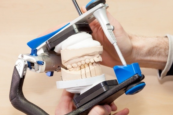Dentist holding a model of the jaws inside of dental adjustment tool