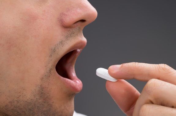 Close up of a person about to swallow a pill