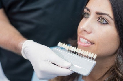 Dentist holding row of veneers in front of woman's smile