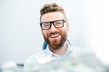 man smiling while sitting in treatment chair 